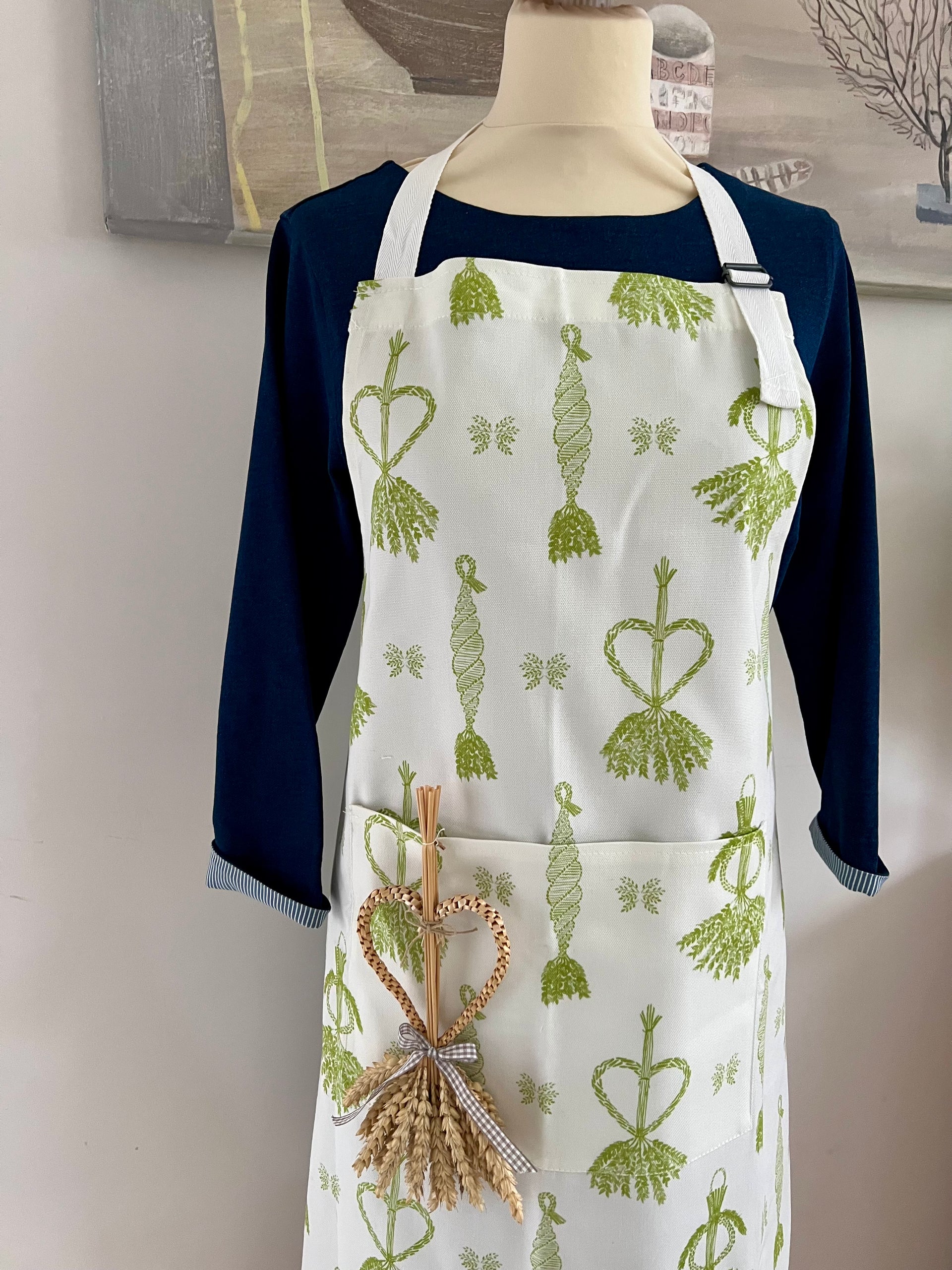 White apron with adjustable neck strap and pocket in fresh green corn dolly print.