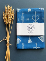 Indigo blue tea towel depicting white corn dolly pattern.