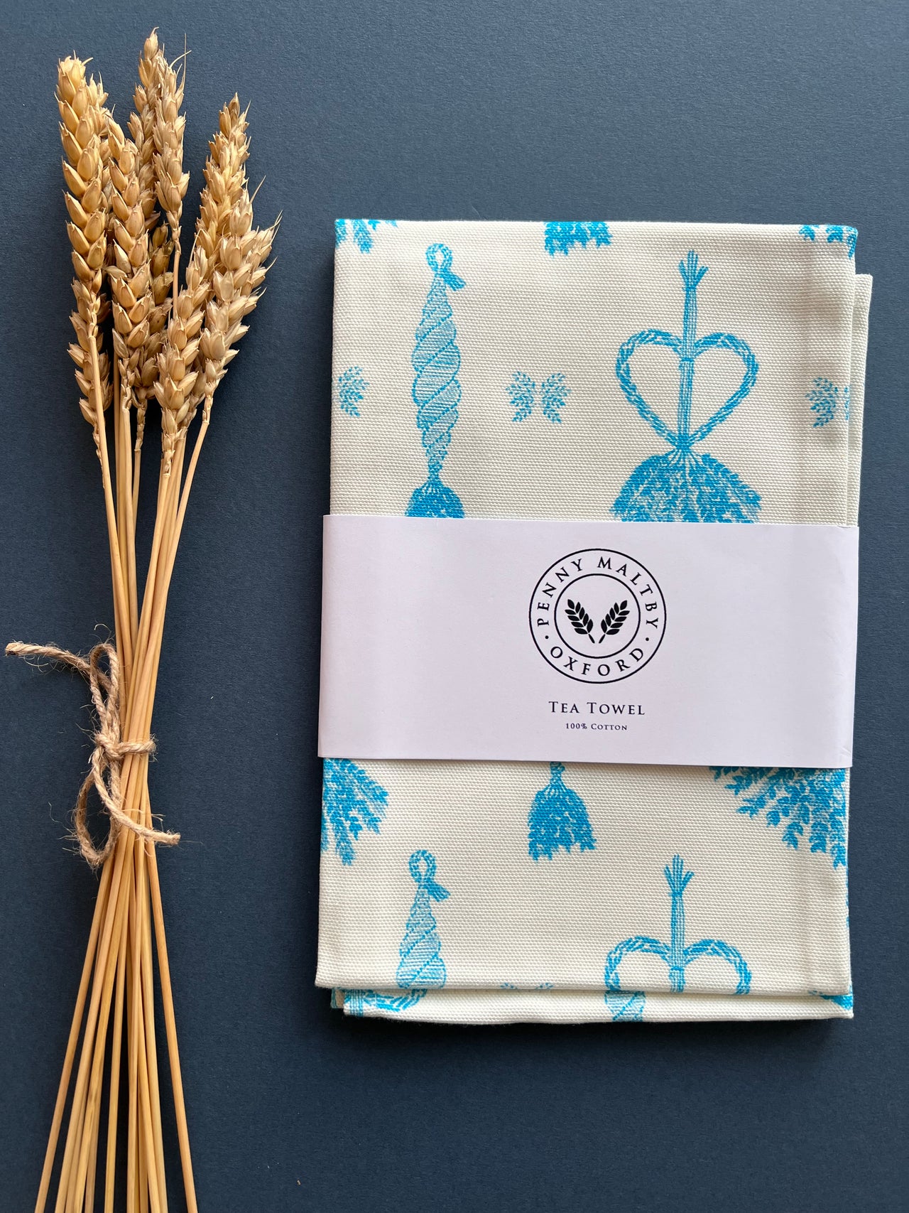 Cotton tea towel in white with bright turquoise blue corn dolly print.