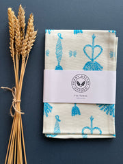 Cotton tea towel in white with bright turquoise blue corn dolly print.