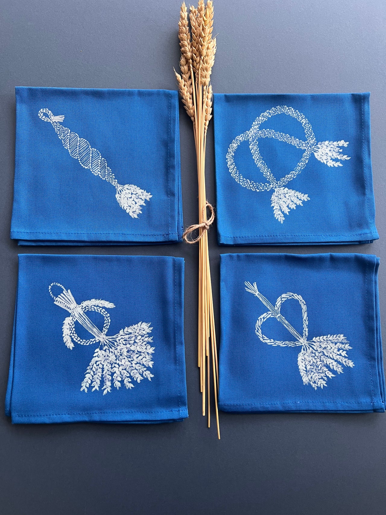 Indigo blue square cotton napkins with white printed corn dolly pattern, each four pack contains one of each design.